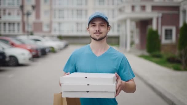 Młody i energiczny dostawca, niosący pizzę i torbę zakupów. Facet wykonuje swoją pracę.. — Wideo stockowe