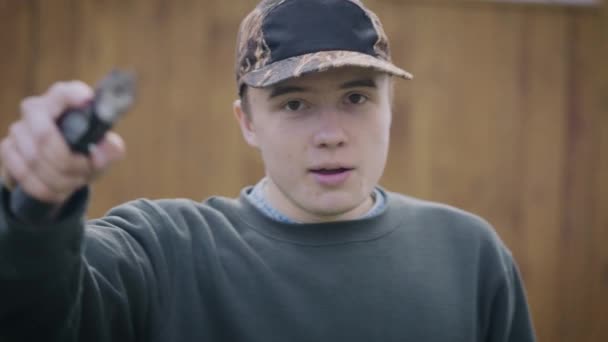 Un adolescent avec une arme dans les mains menace. L'homme est agressif et prêt à agir. — Video