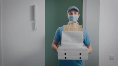 Teslimatçı elinde yemekle bir sipariş tutuyor. Yarı zamanlı bir işte çalışan bir gencin portresi..