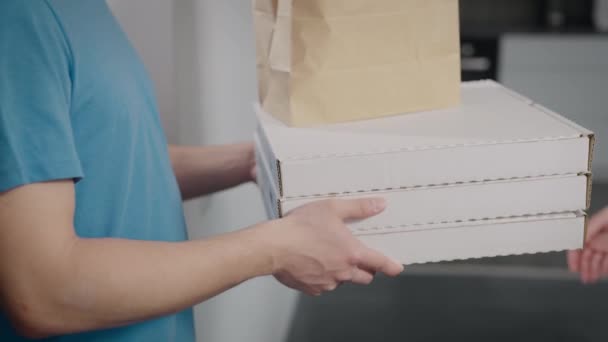 Un repartidor de comida entrega la orden a una mujer. Primer plano de cajas de pizza y paquetes de alimentos. — Vídeo de stock