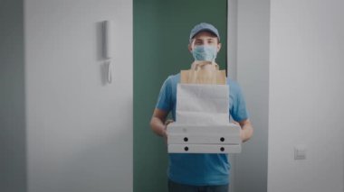 Teslimatçı elinde yemekle bir sipariş tutuyor. Yarı zamanlı bir işte çalışan bir gencin portresi..