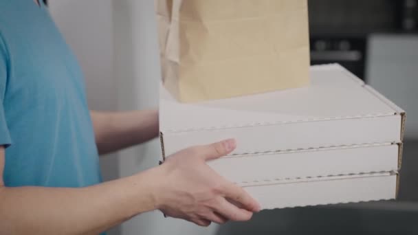 Ein Essenslieferant übergibt den Auftrag an eine Frau. Nahaufnahme von Pizzakartons und Lebensmittelverpackungen. — Stockvideo