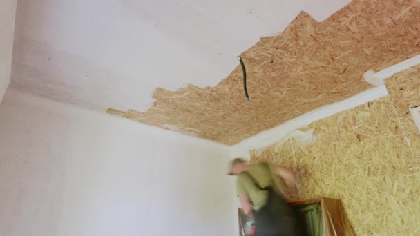 Indendørs renovering tid-lapse. En mandlig arbejder maler loftet fra OSB. Hvid maling er en fremragende løsning til beboelsesejendomme. – Stock-video