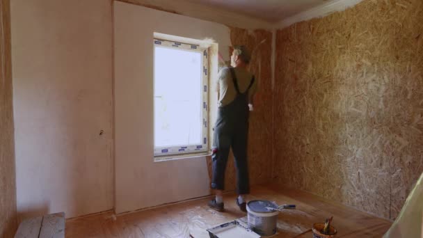 Час відновлення у приміщенні перекривається. Чоловік малює стіни з OSB. Біла фарба відмінне рішення для житлових приміщень . — стокове відео