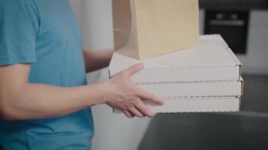 Genç bir teslimatçı eve yiyecek getirdi. Pizza ve abur cubur teslimatı için uygun bir servis..