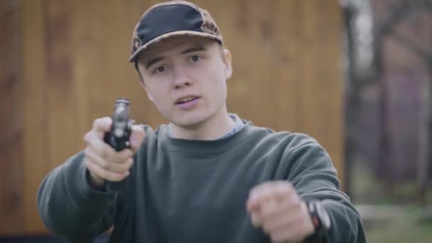 Egy tinédzser pisztollyal a kezében fenyegetőzik. Ez az ember agresszív és kész cselekedni.. — Stock videók