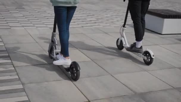 Un bărbat şi o femeie merg cu scuterele electrice. În cadru, picioarele și picioarele scuterelor . — Videoclip de stoc