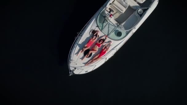 Aerial view. Three beautiful women in red swimsuits are sunbathing while lying on a yacht. — Stock Video