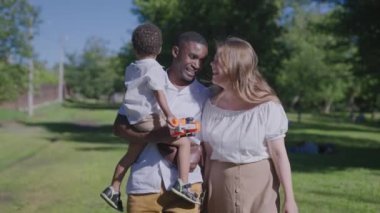 Çok uluslu bir aile parkta yürüyor. Karısı ve çocuğuyla birlikte Afrikalı Amerikalı bir baba..