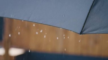 Gri şemsiye yakın çekim. Şemsiyenin yüzeyinden yağmur damlaları akıyor.