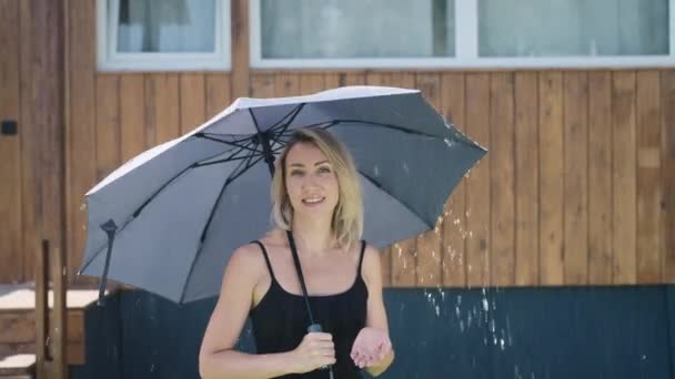 Приваблива блондинка використовує парасольку під час дощу. Жінка під літній душ . — стокове відео