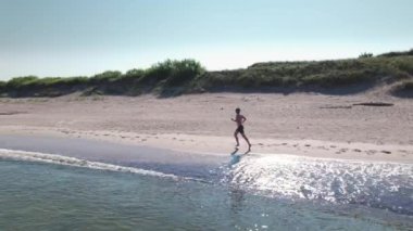 Hava görüntüsü. Deniz kıyısında koşan bir adam.