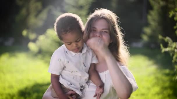 Boldog világos bőrű európai nő afrikai kislányt tart a karjaiban. — Stock videók