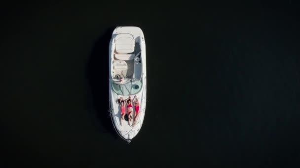 Вид с воздуха. Три красивые женщины в красных купальниках загорают на яхте. — стоковое видео