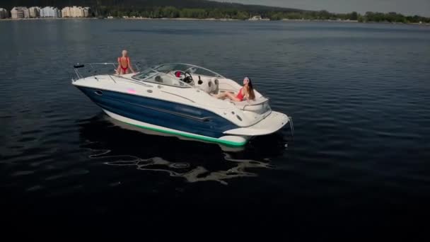 Luchtfoto 's. Drie mooie vrouwen rusten op een motorboot. Modellen in rode zwempakken ontspannen en zonnebaden. — Stockvideo