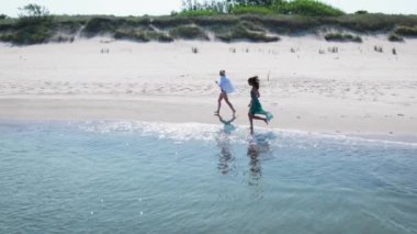 Hava görüntüsü. İki genç kadın deniz kıyısında koşuyor..