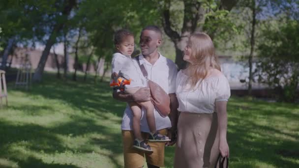 Famille multiraciale ensemble. Journée ensoleillée d'été dans le parc de la ville. Maman papa et fils en vacances un week-end. — Video