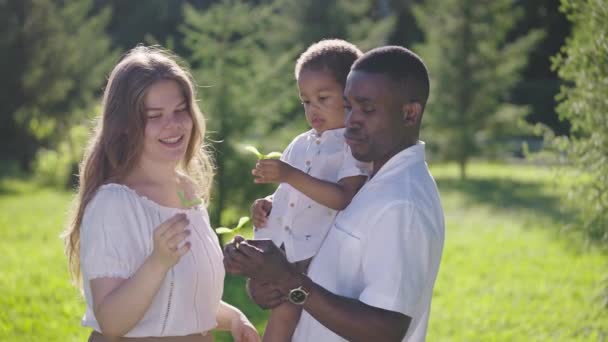 Jovem família multirracial no parque. Mãe pai e menino são felizes juntos. — Vídeo de Stock