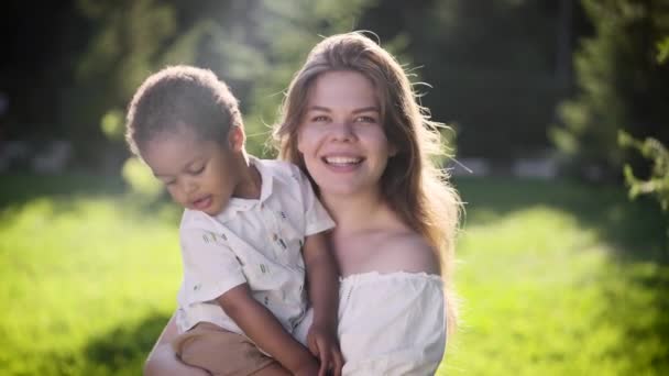 Glückliche hellhäutige Europäerin hält afrikanisches Mädchen auf dem Arm. — Stockvideo