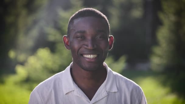 Portrait d'un homme africain heureux dans le parc. Le gars sourit et regarde la caméra. — Video