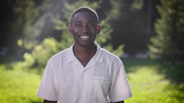 Porträtt av en lycklig afrikansk man i parken. Killen ler och tittar på kameran.. — Stockvideo