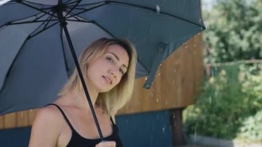Çekici sarışın yağmur sırasında şemsiye kullanır. Yaz duşu altında bir kadın.