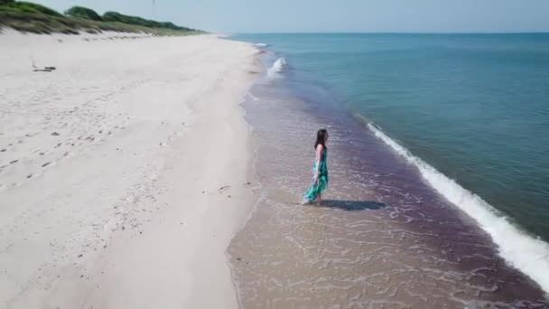Vista aérea. Hermosa mujer en un vestido azul en la orilla del mar Báltico. — Vídeo de stock