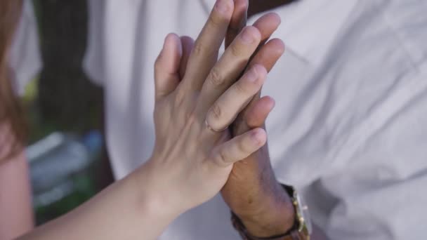 En sort og hvid hånd er sammenflettet. En mand og en kvinde på en romantisk date. Interracial bånd er normen. – Stock-video