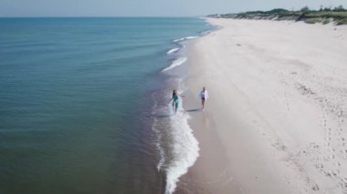 Hava görüntüsü. İki genç kadın deniz kıyısında yürüyor..