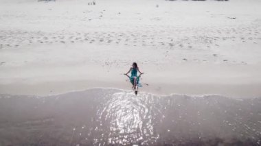 Hava görüntüsü. Mavi elbiseli güzel bir kadın dalgaların yanında yatıyor..
