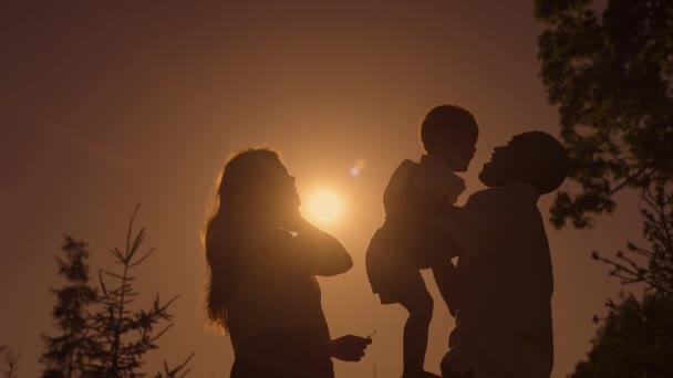 Famille complète au coucher du soleil. Silhouettes de papa maman et fils, famille heureuse ensemble. — Video