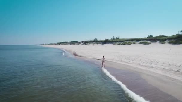 Вид с воздуха. Красивая женщина в купальнике на берегу Балтийского моря. — стоковое видео