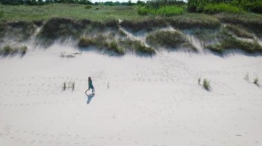 Hava görüntüsü. Genç bir kadın sahilde yürüyor..
