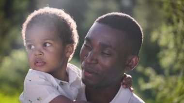 Oğlu ile birlikte Afrikalı bir adamın portresi. Baba ve oğul parkta keyifli..