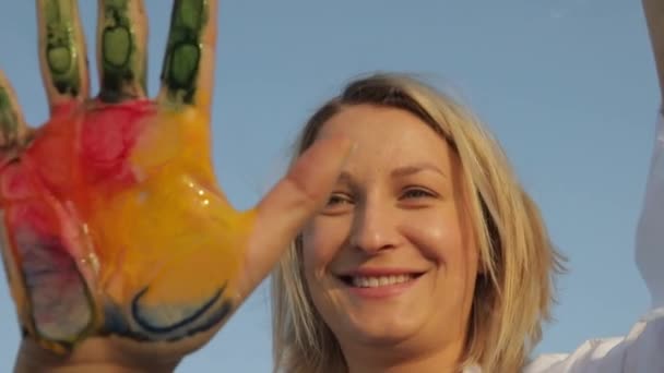 Meisje laat een handafdruk achter met gekleurde verf op het glas — Stockvideo