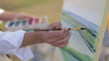 Kız ressam sehpaya resim çizer. Profesyonel sanatçı iş başında.