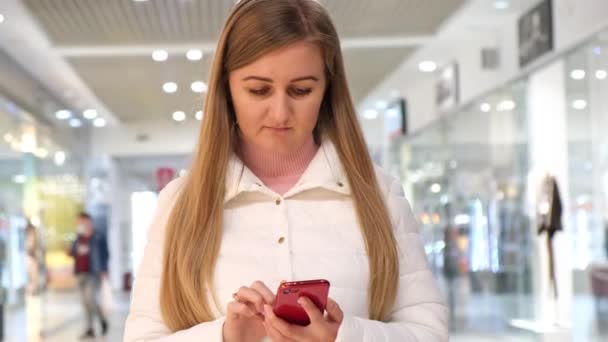 Привлекательная женщина со смартфоном в руках читает свои сообщения — стоковое видео