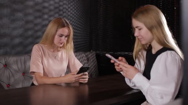 Девушки разговаривают со смартфонами в руках и пьют чай — стоковое видео