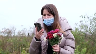 Elinde çiçeklerle akıllı telefondan konuşan bir kızın portresi..