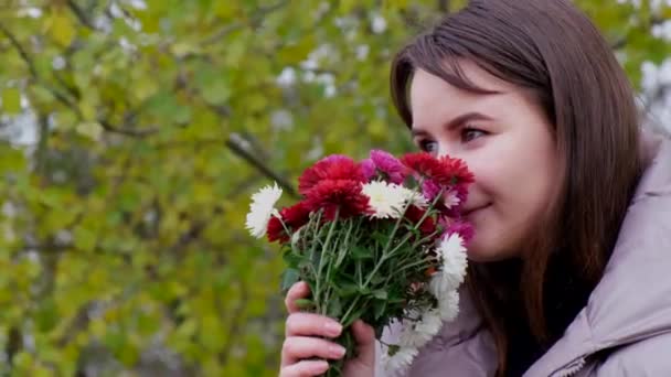 Portrait d'une fille parlant sur un smartphone avec des fleurs dans ses mains. — Video