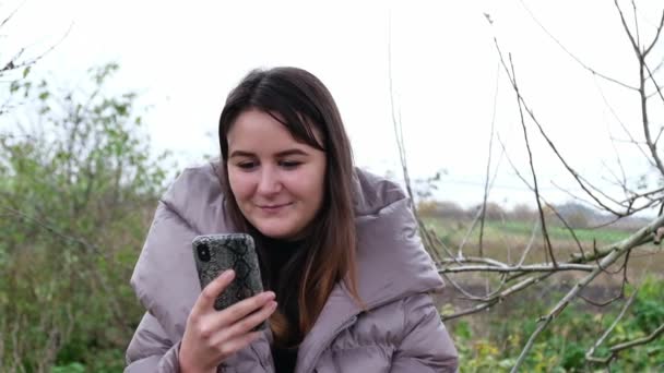 Fille utilise son smartphone sur une balançoire dans le parc — Video