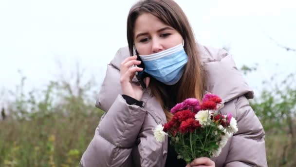 손에 꽃을 들고 얼굴에는 의료용 마스크를 쓴 소녀 — 비디오