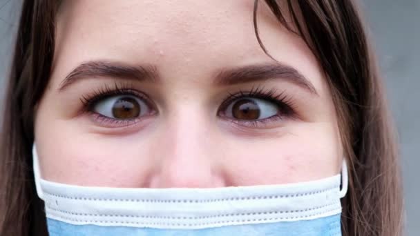 Nahaufnahme Porträt einer jungen Frau in einer medizinischen Schutzmaske. — Stockvideo