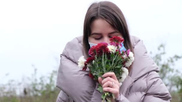 Fille avec des fleurs dans ses mains et un masque médical sur son visage — Video