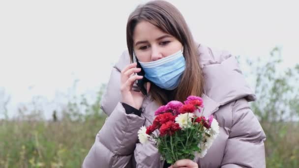 Porträt eines Mädchens, das mit Blumen in der Hand auf einem Smartphone spricht. — Stockvideo