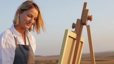 Genç kadın ressam yağlı boyalarla bir resim yapıyor..