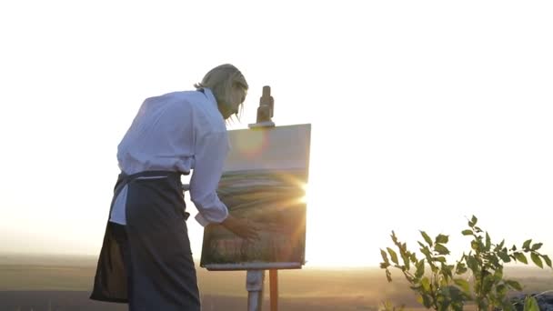 Kız ressam yağlı boyalarla resim yapıyor. Dinlenmek için güzel bir yer. — Stok video