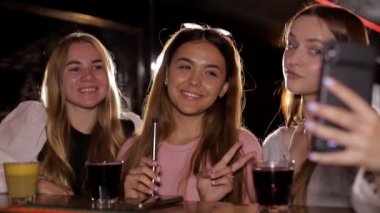 Kafede cep telefonuyla selfie çeken mutlu genç kızlar..