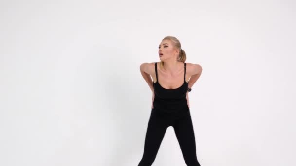 Slim fit fitness girl utför en uppsättning övningar på en grå bakgrund. En flicka i sportig tight svart orm hud konsistens — Stockvideo