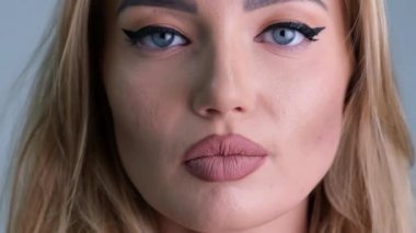 Güzel, genç, sarışın, şehvetli kadın kırmızı seksi dudakları parmağıyla kapatıyor. Açık havada çekilen portrede sessizlik var.